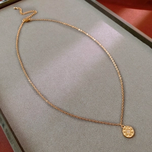 Close-up of golden titanium steel floral pendant necklace on grey velvet jewelry tray