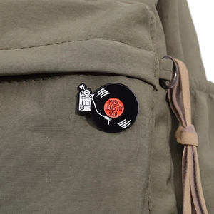 Détail du pin's vintage en émail disque vinyle sur un sac à dos en toile vert armée