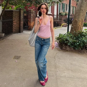 Street style shot of a pink polka dot camisole with blue jeans and silver tote bag