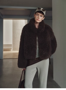 Detail view of a thick dark brown faux fur vest on a model in a minimalist setting