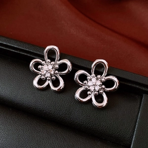 Close-up of hollow flower earrings with zircon center on red silk and black leather