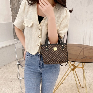 Vintage mini bucket bag with gold geometric print and black leather strap worn by a model
