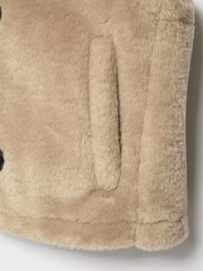 Close-up of the plush faux fur vest side pocket and premium stitching in beige color