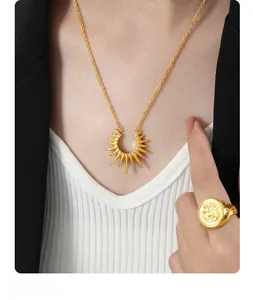 Detailed view of a gold sunburst pendant necklace and signet ring on a fashion model