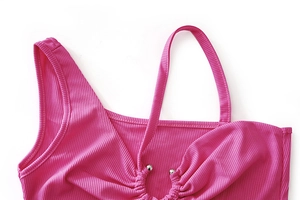 Détail du crop top en maille côtelée rose avec perles argentées et décolleté ajouré