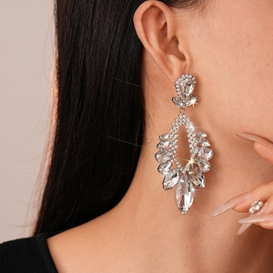 Close-up of sparkling flower-shaped teardrop earrings with crystals worn by a model