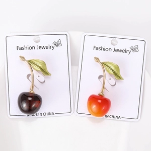 Detailed close-up of cute cherry brooches with gold leaves on display cards
