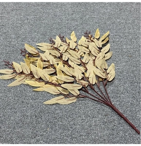 Macro view of artificial willow branch with golden leaves and red-brown stems on gray fabric