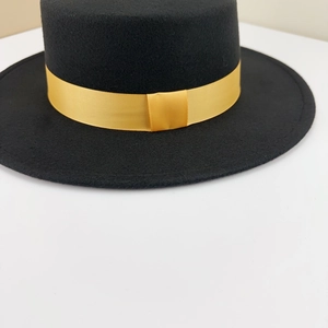 Detail of a black flat top wool fedora hat featuring a bright yellow smooth ribbon band