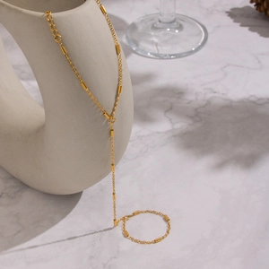Collier long en Y doré élégant suspendu sur un vase minimaliste en céramique blanche