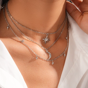 Close-up of triple layered silver necklace with sparkling star and moon pendants on a model