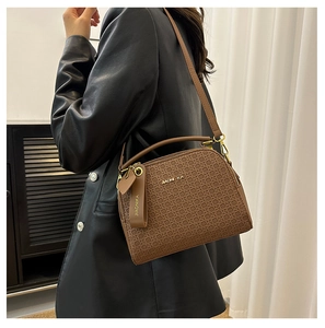 Detail showing JIAONIKA brown woven pattern texture and gold hardware on leather bag