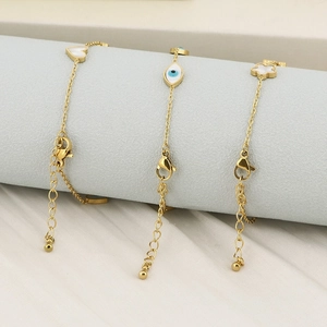 Detailed close-up of golden stainless steel bracelets with heart and evil eye charms