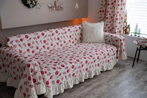 Detailed view of Christmas sofa cover featuring red baubles and elegant ruffled edges
