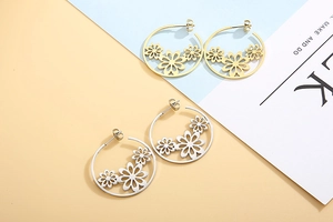 Close-up of gold and silver stainless steel hoop earrings with hollow flower charms