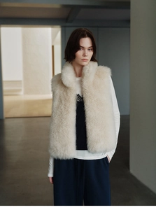 Detail of plush off-white faux fur vest featuring a soft stand collar for women