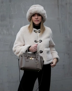 Dettaglio della giacca in pile crema con fibbia, cappello in peluche e borsa in pelle coordinata