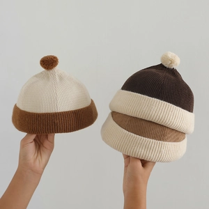 Three children's ribbed knit beanies with fur pom poms in beige and brown color tones
