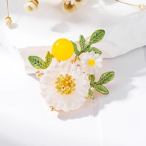 Broche fleur marguerite élégante avec feuilles émail vert et perle jaune sur pierre blanche