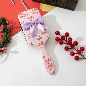 Pink Christmas hair brush set with red holiday patterns and a purple bow decoration