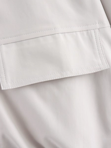 Detailed close-up of the double-stitched pocket on a light gray casual flight jacket