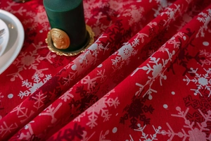 Close-up of red Christmas tablecloth featuring white snowflake prints and fabric texture