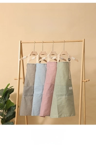 Detail of four colorful striped cotton linen aprons with large pockets for kitchen use