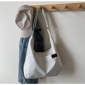 Detailed view of white minimalist canvas tote bag hanging with lifestyle accessories