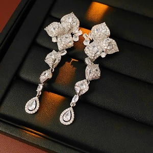 Détail de boucles d'oreilles fleurs et gouttes en argent avec zircons en boîte à bijoux