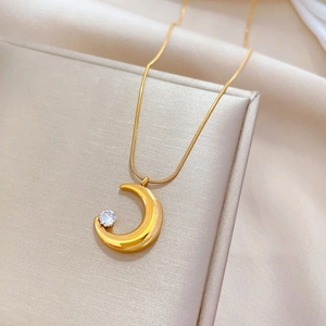 Detailed macro view of a gold moon pendant necklace with a sparkling zircon inlay