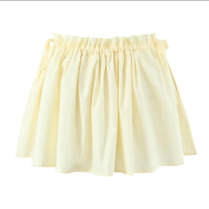 Detail of light yellow mini skirt featuring ruched waist and side tie-up design