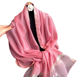 Bufanda rosa translúcida con borde dorado drapeada en un maniquí para primavera