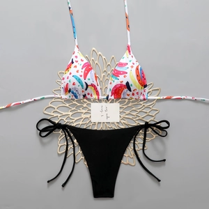 Flat lay of banana print bikini top and black side-tie bottom on gold floral prop