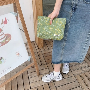 Detail of olive green canvas pouch with delicate floral embroidery and zipper