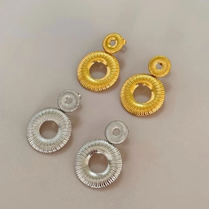 Detailed view of layered circular earrings with pleated sunburst texture in gold and silver
