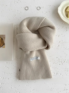 Dettaglio di sciarpa in lana a maglia grossa beige crema con etichetta fatta a mano