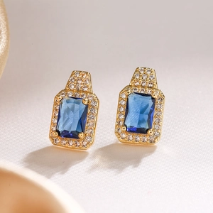 Macro shot of gold-plated square stud earrings with dark blue sapphire cubic zirconia