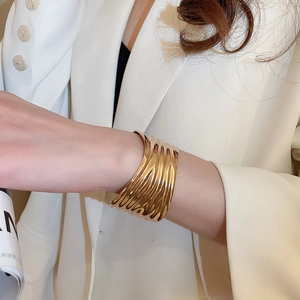 Detail shot of a golden wide cuff bracelet featuring unique irregular ripple textures