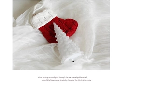 Close-up of white acrylic Christmas tree lamp with icy texture and knitted holiday sock
