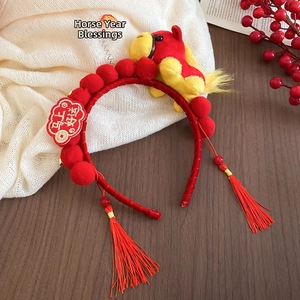 Detail of red New Year headband with plush horse doll, gold charms and festive tassels