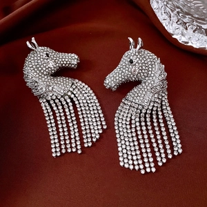 Detailed close-up of horse head earrings with white rhinestones on dark red silk