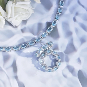 Close-up of silver jewelry set with light blue oval gemstones and diamond accents