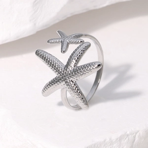 Detail of silver starfish ring with textured metal finish on white stone backdrop