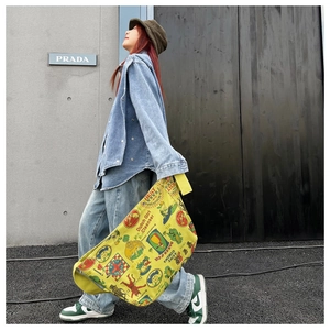 Detail view of yellow canvas messenger bag with vintage prints worn by model in street