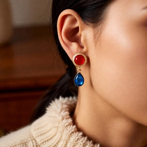 Close-up of vintage resin drop earrings with red and blue stones in gold finish