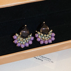 Macro detail of purple teardrop crystal earrings with beaded retro design in jewelry box