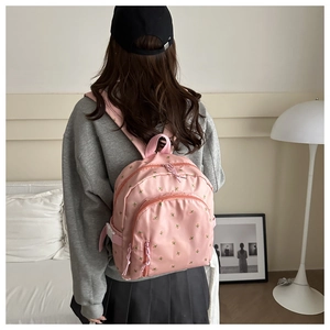 Pink floral backpack shown on model with casual grey hoodie and pleated skirt