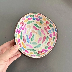 Detail of handcrafted coconut shell bowl with colorful hand-painted fish patterns