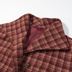 Detail view of red plaid wool coat collar with luxury button and silk lining texture