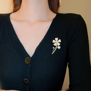 Détail d'une broche fleur avec nacre et perles portée sur un cardigan noir élégant